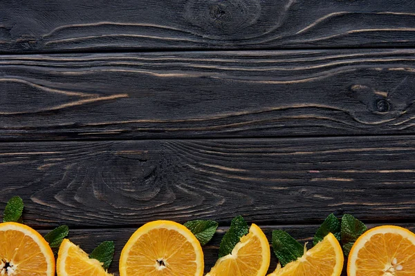 Vista superior de rodajas de naranja fresca y hojas de menta sobre fondo de madera - foto de stock