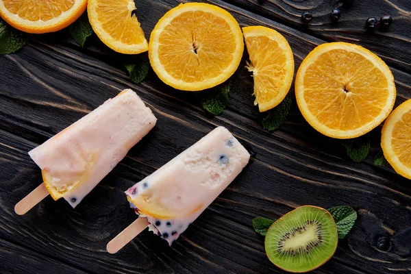 Vista dall'alto di deliziosi gelati fatti in casa con frutta e menta sulla superficie di legno — Foto stock