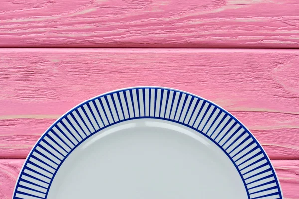 Top view of empty round plate on pink wooden table top — Stock Photo