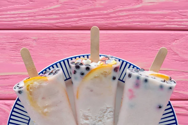 Blick von oben auf süßes leckeres hausgemachtes Eis mit Früchten und Beeren auf Teller auf rosa Holztisch — Stockfoto