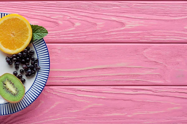 Vue du dessus des fruits frais mûrs et des baies sur plateau en bois rose — Photo de stock