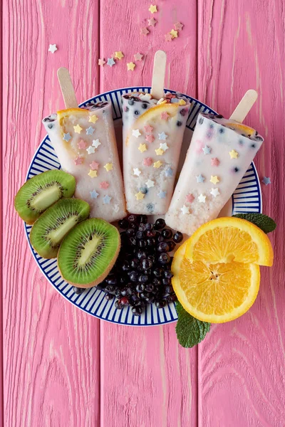 Vista superior de sorvete caseiro doce com frutas frescas e bagas no prato na mesa de madeira rosa — Fotografia de Stock