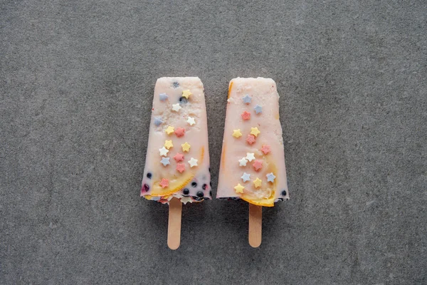 Top view of sweet tasty popsicles on sticks on grey — Stock Photo