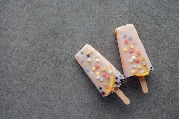 Top view of delicious cold popsicles on sticks on grey background — Stock Photo