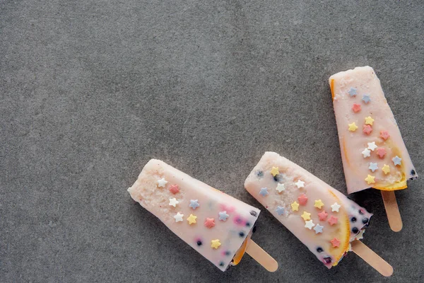 Top view of sweet tasty popsicles on sticks on grey background — Stock Photo