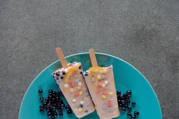 Top view of sweet cold popsicles with berries on plate on grey — Stock Photo