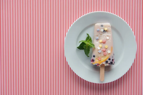Вид сверху на вкусное домашнее мороженое с мятой на тарелке на полосатом фоне — стоковое фото