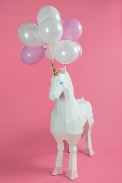 Toy unicorn under pink and white balloons on pink background — Stock Photo