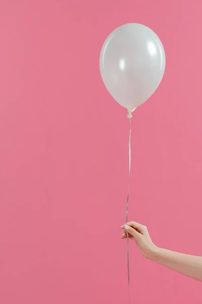 Vista recortada de una mujer sosteniendo un solo globo blanco aislado en rosa - foto de stock