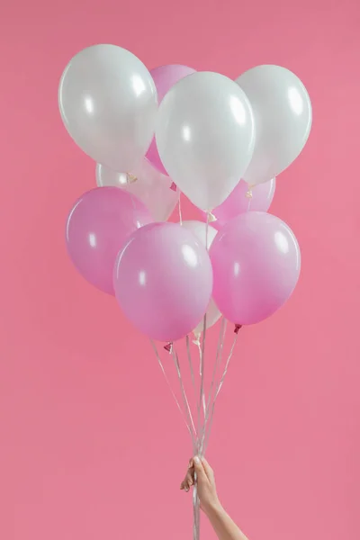 Vista ritagliata di tenere palloncini rosa e bianchi in mano ragazza isolato su rosa — Foto stock