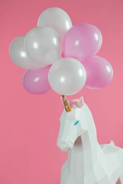 Bunch of air balloons on horn of toy unicorn isolated on pink — Stock Photo