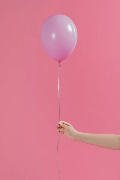 Vista ritagliata di donna che tiene singolo palloncino rosa isolato su rosa — Foto stock