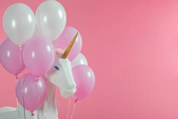 Spielzeug-Einhorn zwischen rosa und weißen Luftballons isoliert auf rosa — Stockfoto