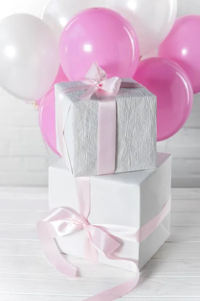 Stacked present boxes and bright balloons on white brick wall background — Stock Photo