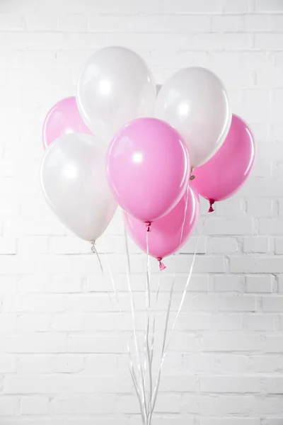 Ballons roses et blancs sur fond de mur de briques blanches — Photo de stock