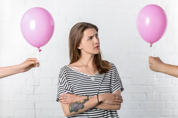 Nachdenkliche junge Frau schaut auf Hand hält Luftballon auf weißem Backstein Wand Hintergrund — Stockfoto