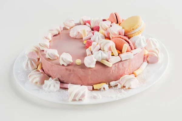 Close up of pink cake with marshmallows and macarons on white plate — Stock Photo