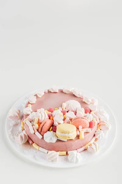Rosa Kuchen mit Marshmallows und Macarons auf weißem Teller mit Kopierraum — Stockfoto