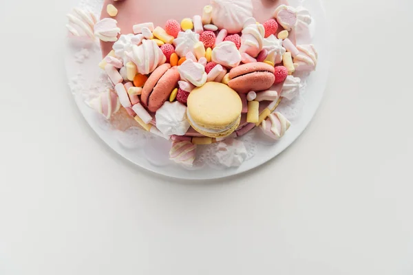 Top view of pink cake with marshmallows and macarons on white plate with copy space — Stock Photo