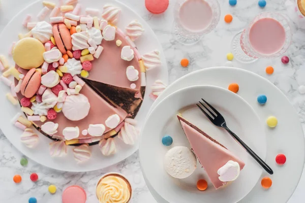 Vista superior de pastel de cumpleaños, caramelos, magdalenas dulces y batido en vasos en la mesa - foto de stock