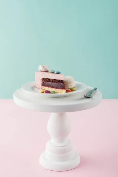 Piece of cake with marshmallow and candies on plate with fork on cake stand — Stock Photo
