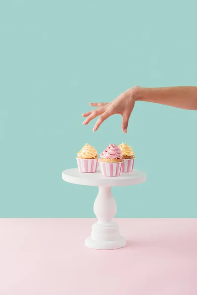 Vue recadrée de femme prenant des cupcakes de stand de gâteau — Photo de stock