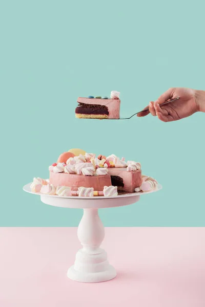 Cropped view of woman holding piece of cake on shovel over big cake on stand — Stock Photo