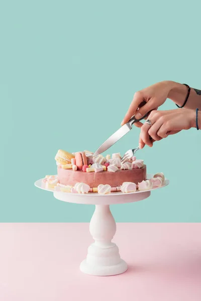 Vista recortada de mujer corte tarta de malvavisco con cuchillo y tenedor en pie de pastel — Stock Photo