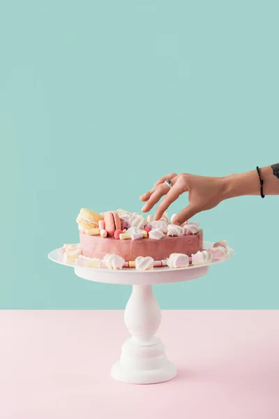 Cropped view of woman taking marshmallow from sweet cake on stand — Stock Photo