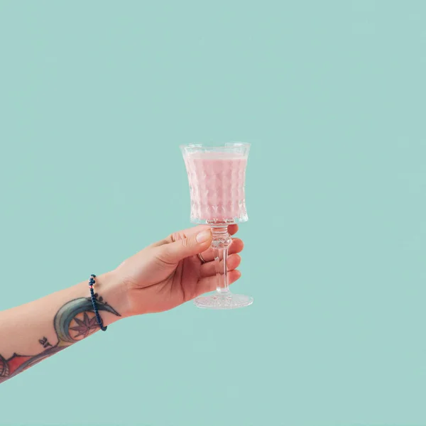 Cropped view of tattooed hand with glass of milkshake isolated on blue — Stock Photo