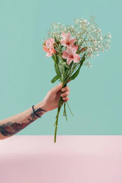Vue recadrée de femme tatouée tenant bouquet avec des fleurs de lis rose — Photo de stock