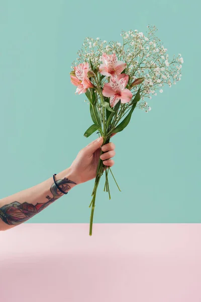 Vista cortada de mulher tatuada segurando buquê com flores de lírio rosa — Fotografia de Stock