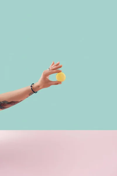 Vista cortada da mão tatuada com macaron amarelo — Fotografia de Stock