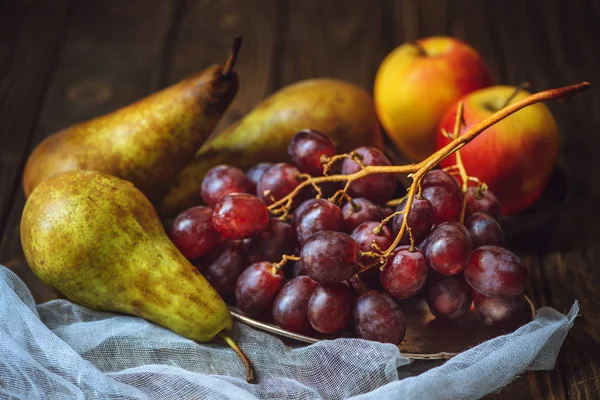 Primer plano de uvas maduras con peras y manzanas sobre mantel de queso - foto de stock