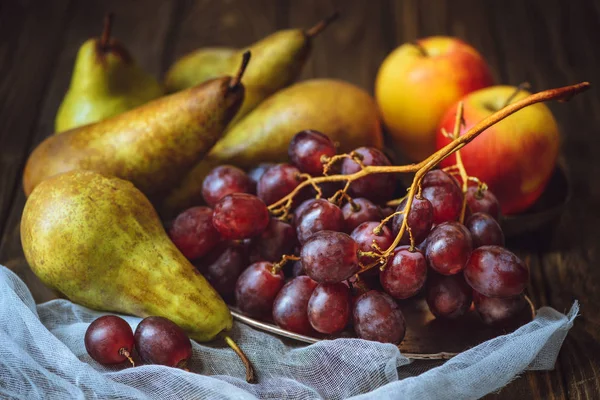 Primer plano de uvas jugosas con peras y manzanas en mantel de queso - foto de stock