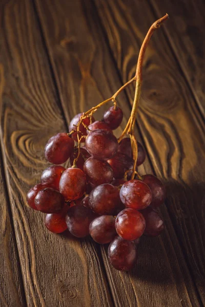 Primer plano de uvas rojas maduras sobre mesa de madera rústica - foto de stock