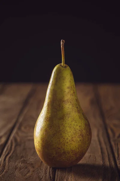Close-up shot of ripe yellow pear on rustic wooden table on black — Stock Photo