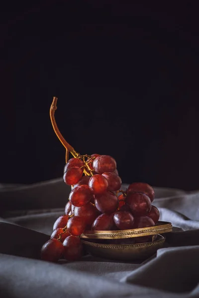 Close-up shot of fresh red grapes on grey drapery on black — Stock Photo