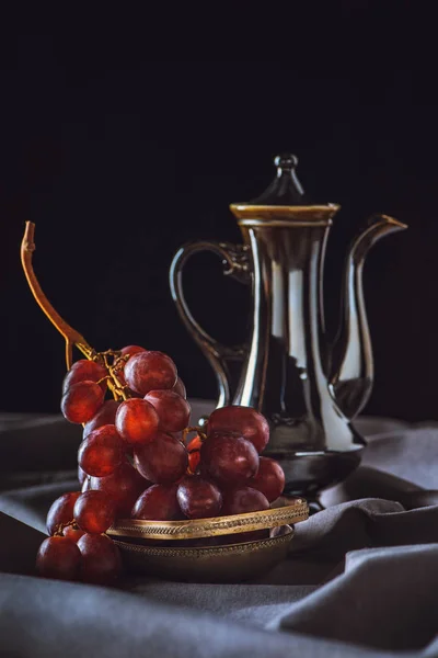 Close-up shot of red grapes with vintage turkish teapot on black — Stock Photo