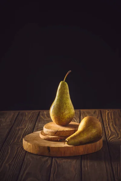 Gros plan de poires mûres sur des planches empilées et sur une table rustique en bois noir — Photo de stock