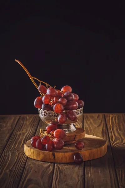 Close-up shot of ripe grapes in vintage metal bowl on rustic wooden table on black — Stock Photo