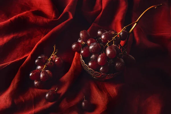Close-up shot of fresh grapes in vintage metal bowl on red drapery — Stock Photo