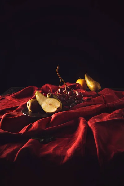 Primer plano de uvas y peras sobre una cortina roja - foto de stock