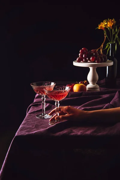 Copos vintage de stand de vinho com uvas e maçãs na mesa com cortinas em preto — Fotografia de Stock