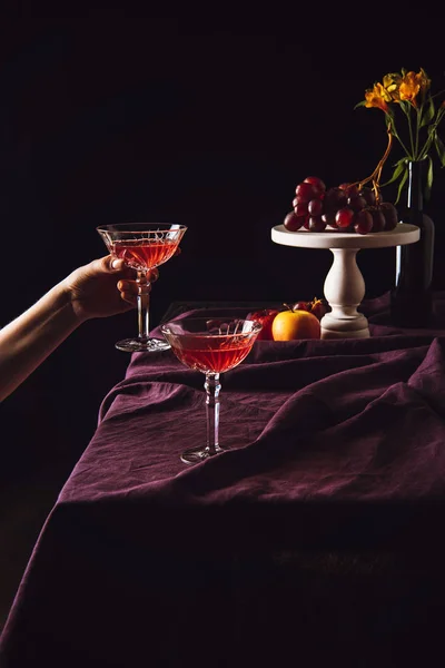 Plan recadré de femme prenant un verre de vin de table avec des fruits sur noir — Photo de stock