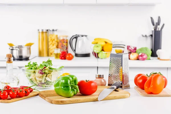 Ripe vegetables, knife and grater on table in light kitchen — Stock Photo