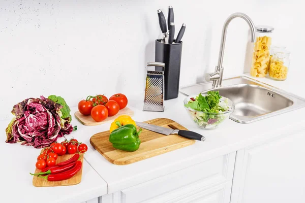 High angle view of bell peppers and knife on cutting board in light kitchen — Stock Photo