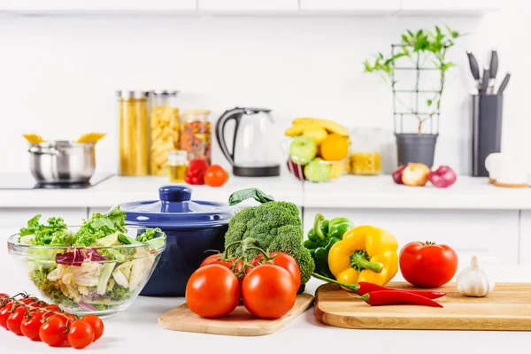 Ripe broccoli, tomatoes and bell peppers on table in light kitchen — Stock Photo