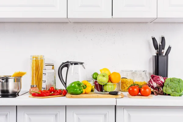 Tasty raw tomatoes and bell peppers on cutting boards in light kitchen — Stock Photo