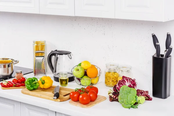 Delicious tomatoes and bell peppers on cutting boards in light kitchen — Stock Photo